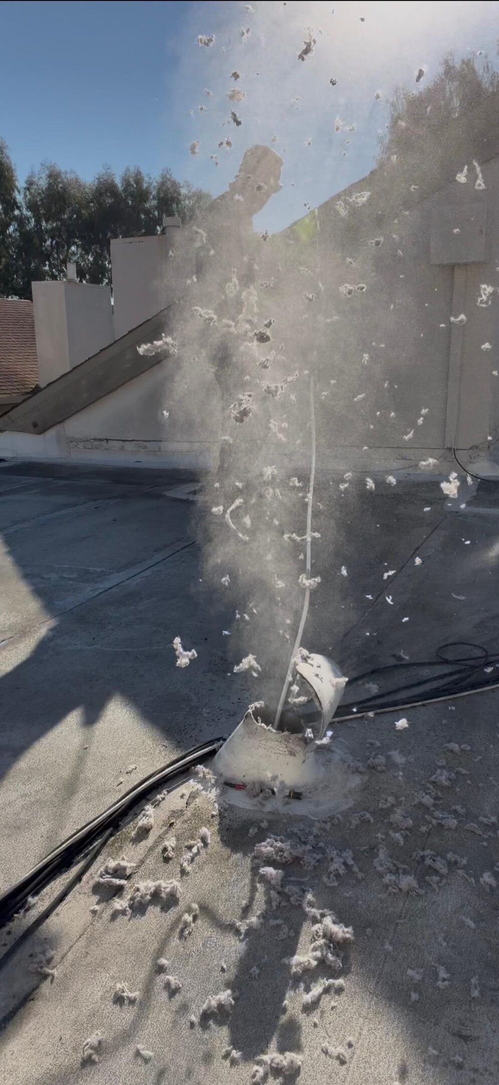 A damaged electrical box on a rooftop emits smoke and debris, with scattered insulation or paper particles floating in the air.